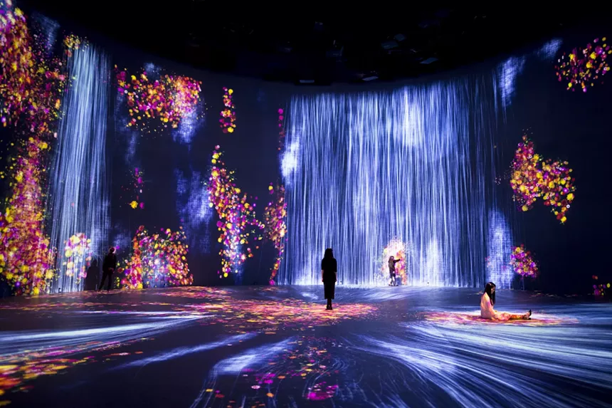 Three people inside an immersive exhibit with colorful wall projections