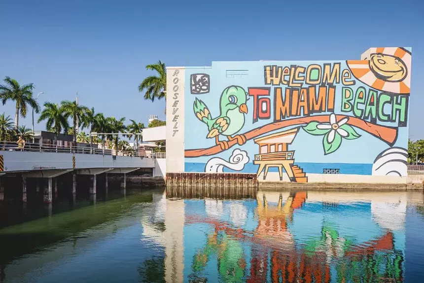 a mural depicting a bird and a lifeguard stands reads, "Welcome to Miami Beach"