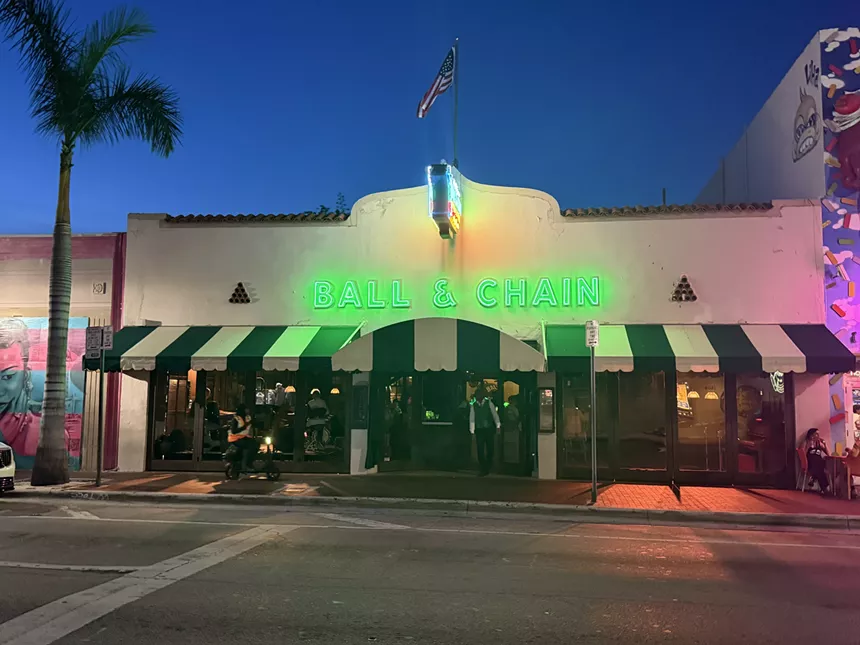 The front of a building with a green neon sign