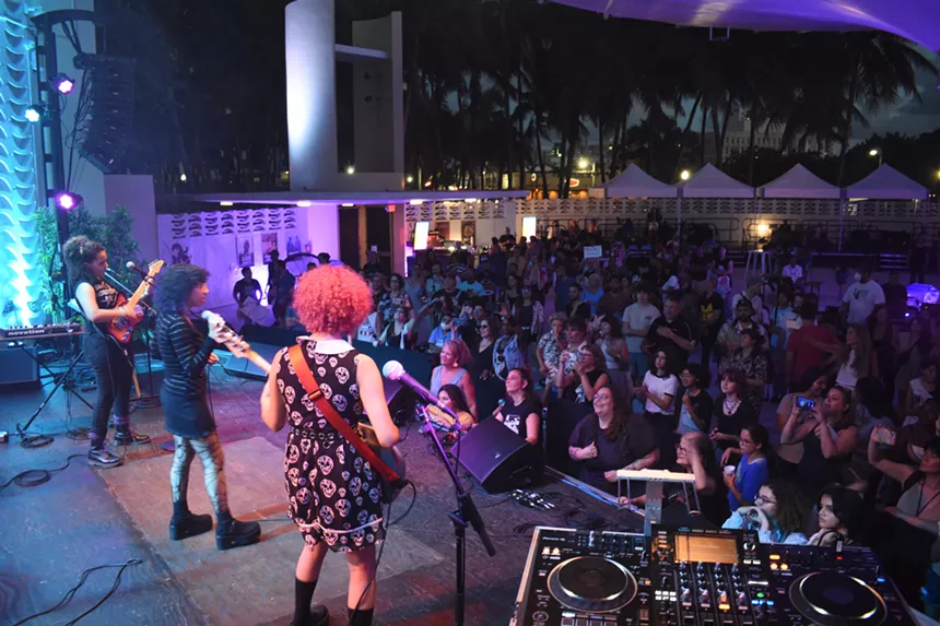 A band of young girls performing in front of a crowd.