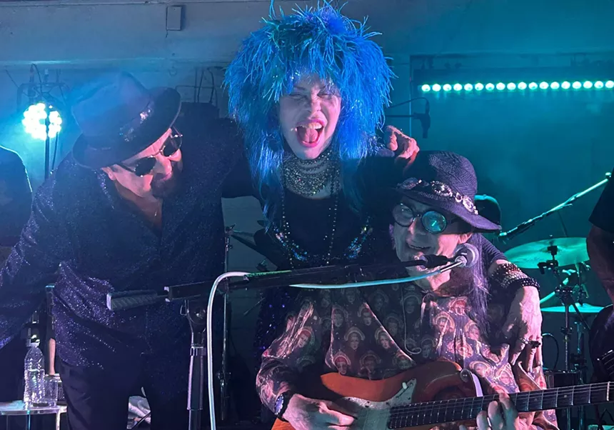 Three band members on stage posing for a picture.