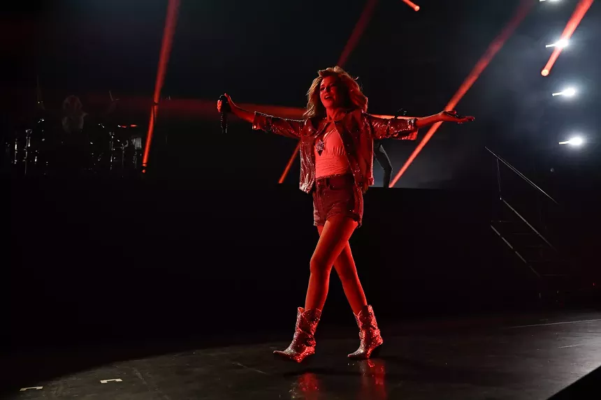 A woman walking on stage under red lights.