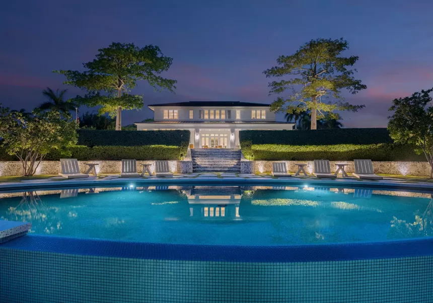 Picture of a pool and a mansion at night.