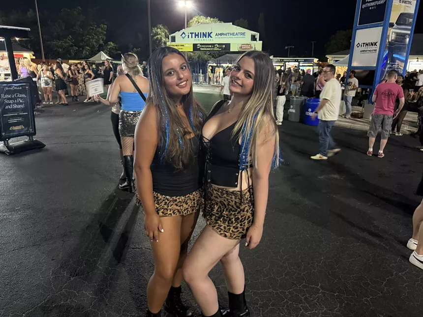Two young women wearing animal print skirts and black tops at a concert.