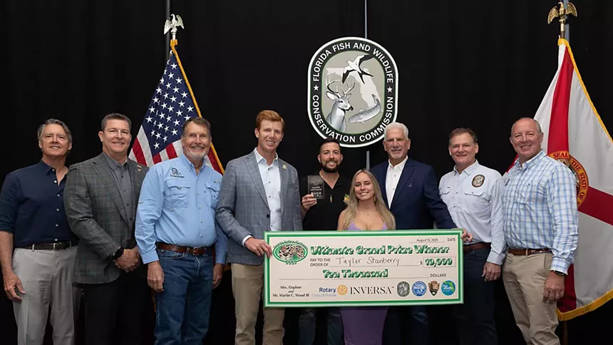 A woman poses with FWC commissioners after winning Florida's Python Challenge 2025.