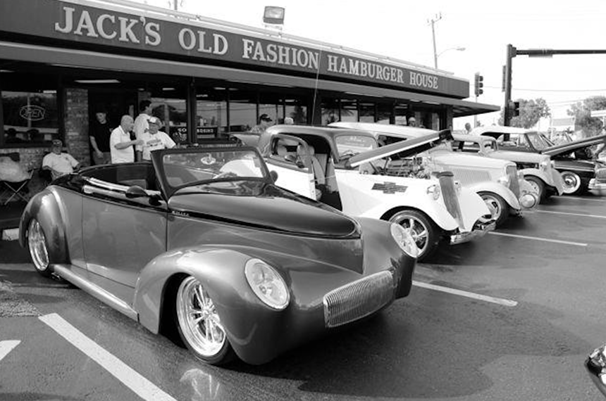 a black and white photograph of vintage cars parked in front of a restaurant