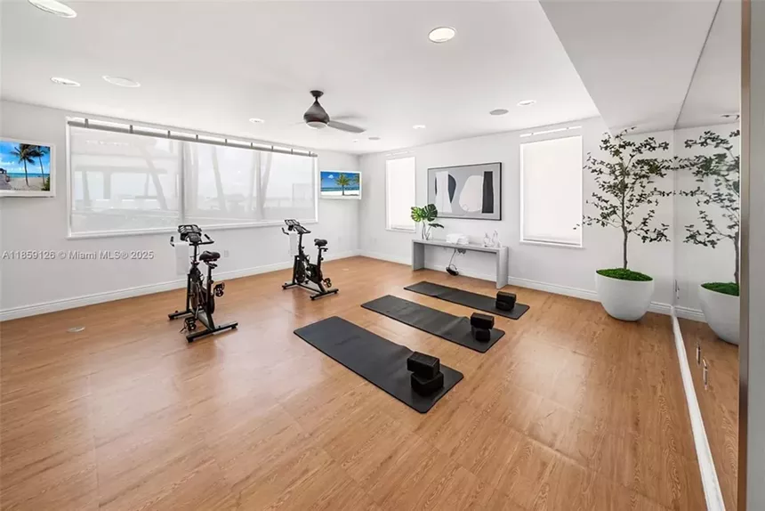 An expansive in-home gym is pictured with two stationary bikes and three yoga mats.