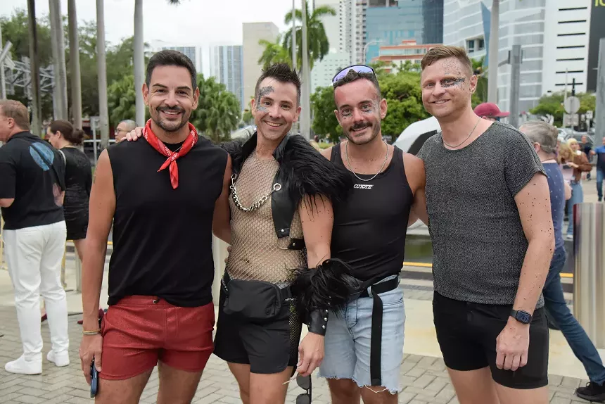 four people stand outside an arena wearing face glitter and mesh