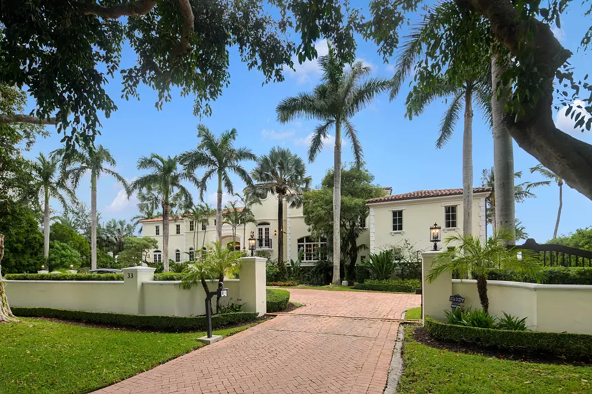 driveway view of the cream-colored mansion