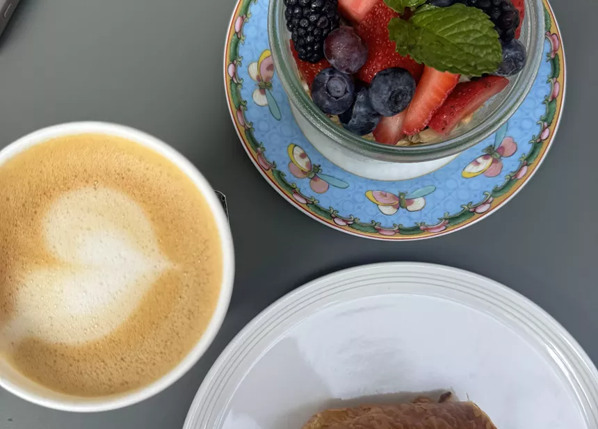 a latte and a bowl of berries on a gray table