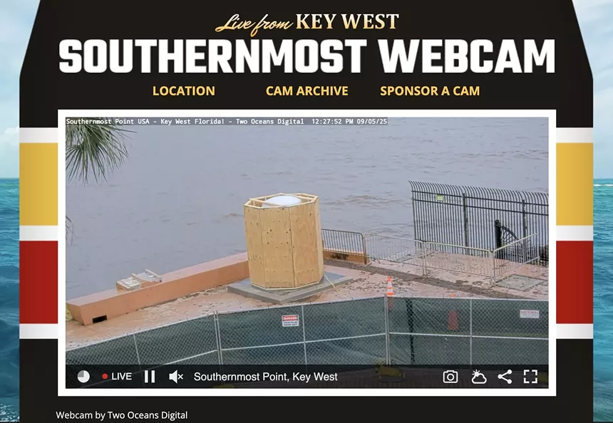Screenshot of a webcam website reading: "Live from Key West, Southernmost Webcam. Location. Cam Archive. Sponsor a Cam." The video shows a white object surrounded by plywood behind fencing in front of the ocean