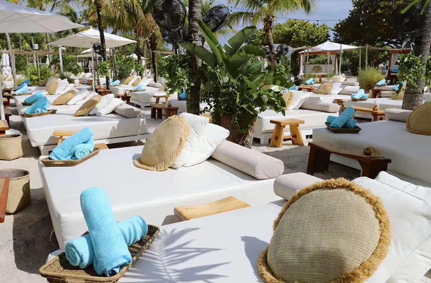 Beach cabana beds with blue towels at Nikki Beach, a dayclub in Miami Beach