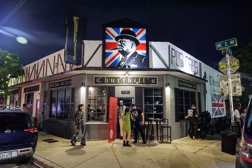 Facade of a dive bar with a painting of Churchill backed by the Union Jack. The sign in the front reads, "Churchill's"