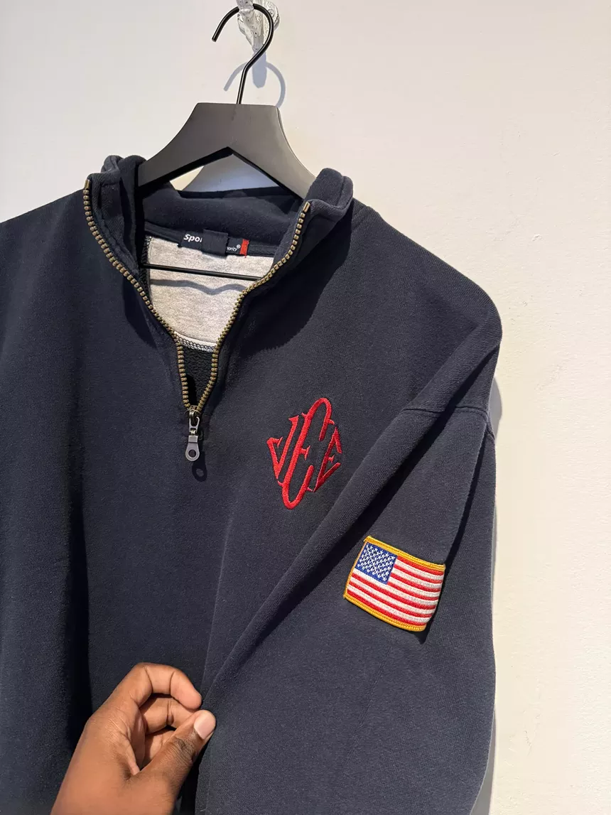 Navy sweatshirt on a hanger with "JEE" red monogram and an American flag patch