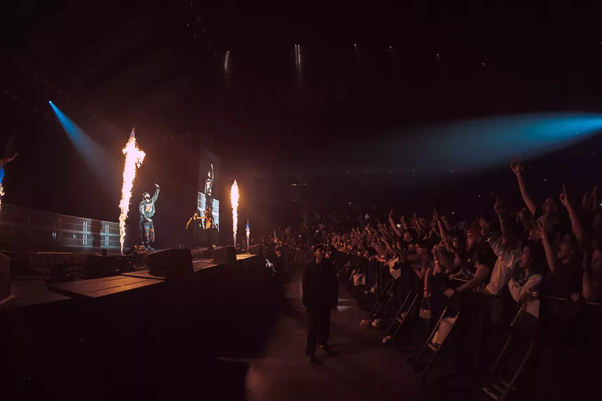 A singer on a stage with fire behind him.