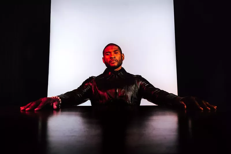 Image: Usher with his arms stretched on a table