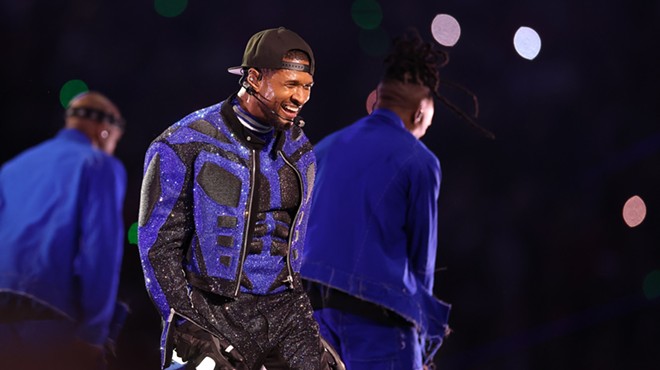 Usher performing onstage in a blue and black sequin outfit