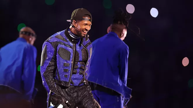 Usher performing onstage in a blue and black sequin outfit