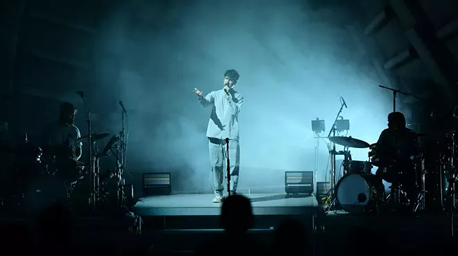 a band performing on an amphitheater stage under eerie, cloudy lighting