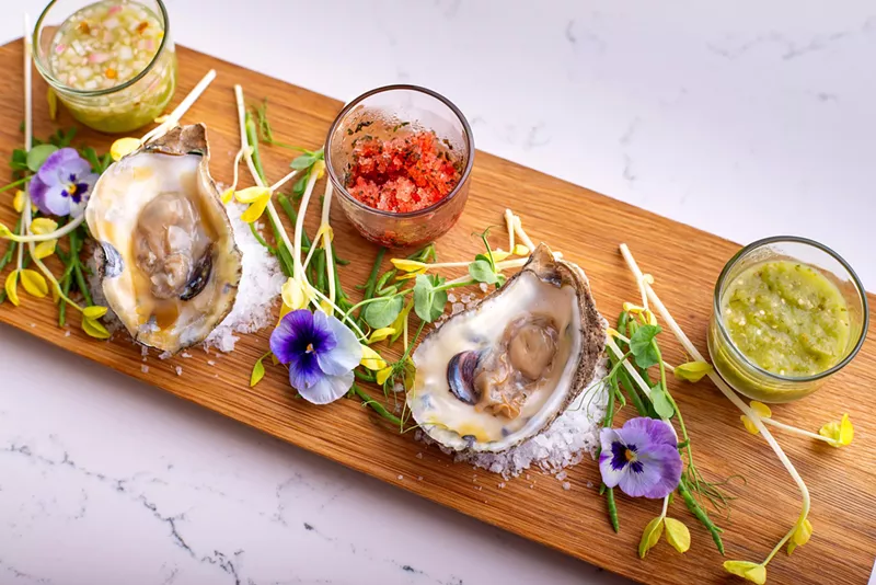 Image: A platter of oysters and herbs on a wooden cutting board.
