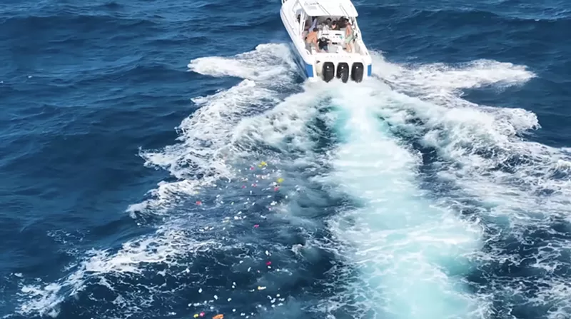 Image: youtube screenshot of a three-engine fishing boat in choppy water with garbage strewn in its wake