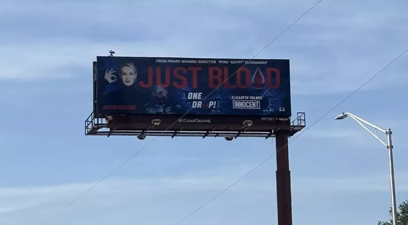 Image: A billboard shows a blonde woman with the words "just blood" in bold print beside her.