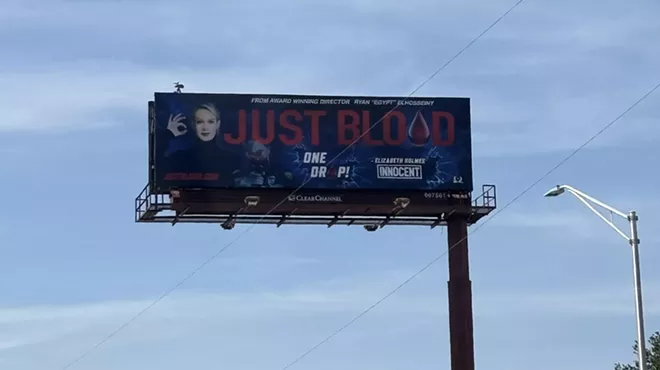A billboard shows a blonde woman with the words "just blood" in bold print beside her.