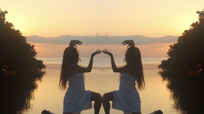 Still image from Caracoles en Cemento of a woman mirrored as she kneels with a sunset behind her