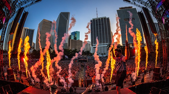 DJ performing on the main stage at Ultra in front of a huge crowd against the downtown Miami skyline